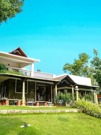 An exterior shot of the villa, surrounded by lush lawns and greenery.