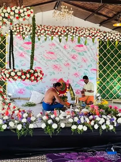 A behind-the-scenes shot of a naming ceremony setup in progress. This image shows the floral arch and cradle being assembled, offering a glimpse into the creation process.