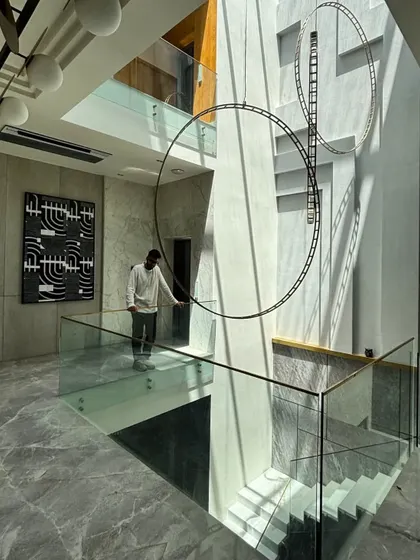 The Step Maze House features a triple-height atrium with a large skylight at its core. This void lights the heart of the home, and the glass balustrade staircase running alongside it emphasizes the dramatic verticality of the space.