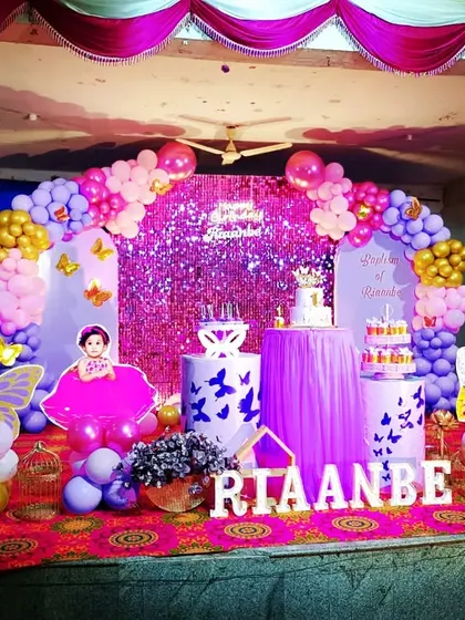 A glamorous butterfly theme for Riaanbe's first birthday. The purple sequin backdrop adds a lot of sparkle, complemented by a pink and purple balloon arch and photo cutouts of the birthday girl.
