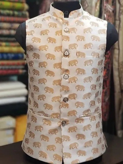 A unique Nehru jacket made from a cream-colored fabric with a gold elephant print. This is a great example of a fun, festive design.