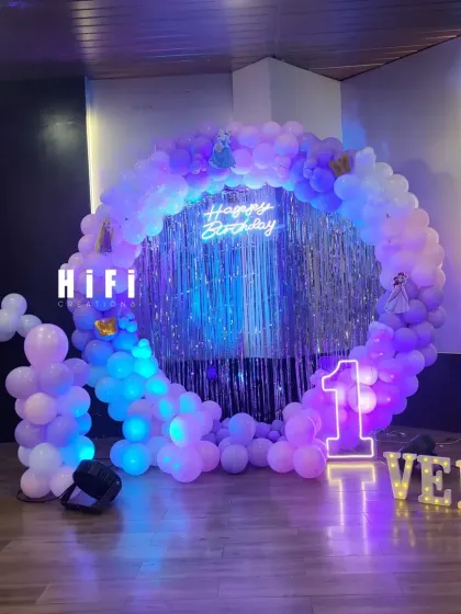 Another angle of the 'Frozen' themed first birthday party. This view shows the full scale of the circular balloon backdrop and the placement of the light-up marquee letters spelling the name 'VEDA', creating a personalized and enchanting photo corner.