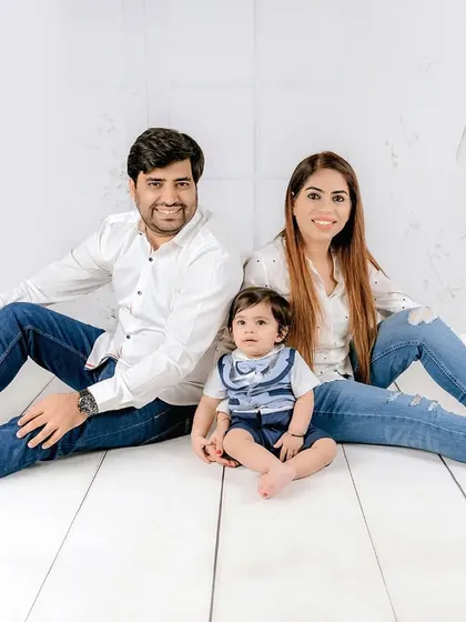 A casual and cool family portrait with everyone in jeans and white shirts, sitting together on a white wood floor. It’s a modern and relaxed take on the family photo.