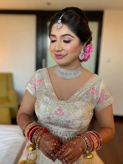 A beautiful portrait of the bride, her hair styled in a classic updo with a fresh pink rose.