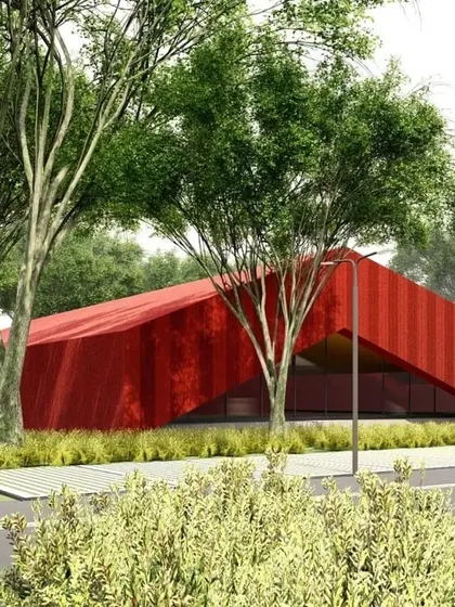 The red building seen nestled among trees, demonstrating how even bold, abstract forms can be integrated thoughtfully into a natural setting.