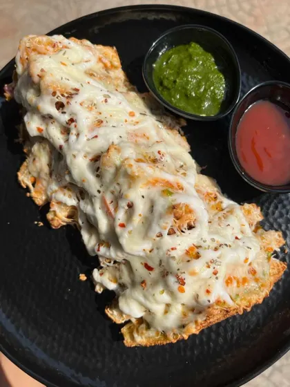 A top-down view of my loaded grilled sandwich, covered in a blanket of melted cheese and served with two classic chutneys.