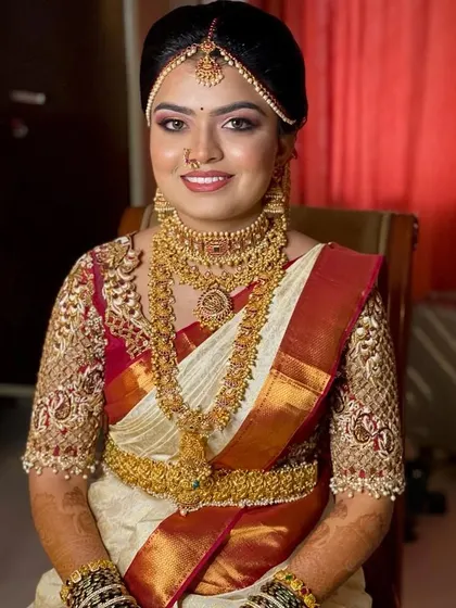 This is my beautiful client on her wedding day, wearing a classic temple jewellery set. The off-white saree with the red border is a timeless choice, and the jewellery adds the perfect touch of tradition.