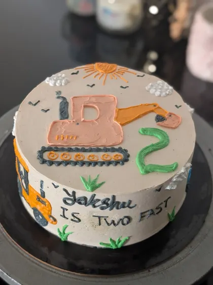 A hand-piped bulldozer cake for a second birthday. This buttercream design has a charming, rustic feel and is perfect for a "Two Fast" party theme.