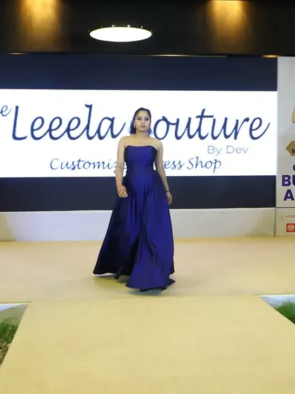 A model takes center stage in a custom navy blue strapless ball gown during the Celebrity Business Awards show. The minimalist design highlights the rich fabric and expert tailoring.