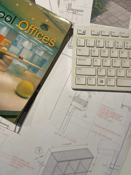 A flat lay of our work desk, covered in technical drawings, reference books, and a keyboard. This image captures the buzz of the studio as we craft spatial identities for brands across India and the UAE.