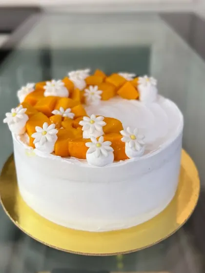 A side view of the fresh mango and daisy cake.