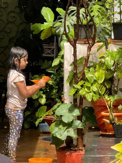 A young child carefully waters the plants, a quiet and focused moment of play that also teaches responsibility and care for living things.