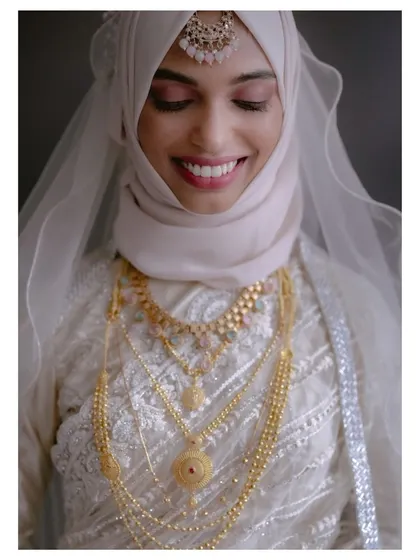 A serene portrait of the bride in her white and gold wedding outfit, her gentle smile reflecting a sense of peace and happiness.