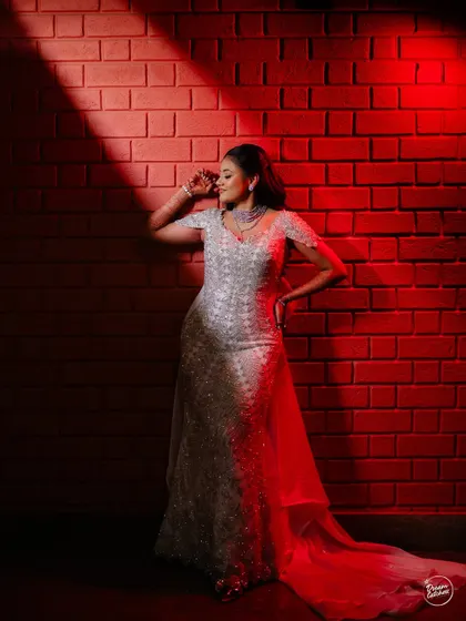 A stunning solo portrait of the bride at her cocktail party. The dramatic red lighting and her elegant pose create a powerful and glamorous image that highlights her style.