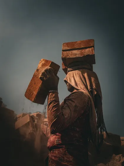 A woman carries her load at a brick kiln, her form silhouetted against the sky. This image is from my long-term project documenting the strength and dignity of laborers who build our world one brick at a time.