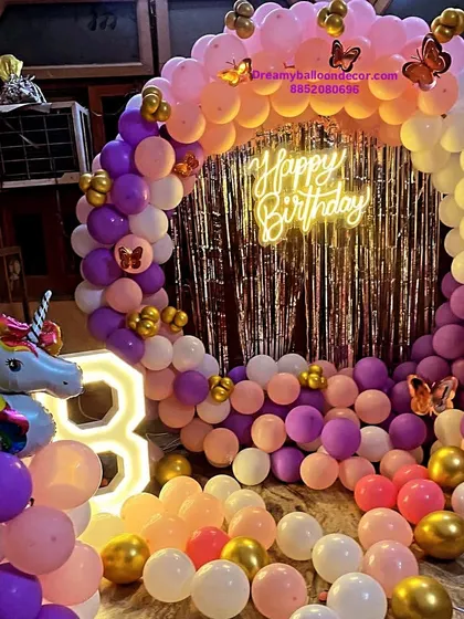 A grand unicorn and butterfly themed decoration for a 3rd birthday. This setup includes a full balloon ring, a large light-up marquee number, and a unicorn foil balloon, creating a magical atmosphere.