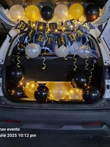 A car boot or dickey decoration is a great way to surprise someone. This setup includes a 'Happy Birthday' banner, fairy lights, and balloons in black, gold, and silver, creating a perfect movie-style surprise moment.