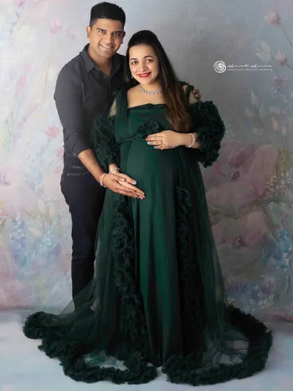 A beautiful couple's portrait in a rich green gown. The way they hold each other shows their strong bond as they prepare to welcome their baby.