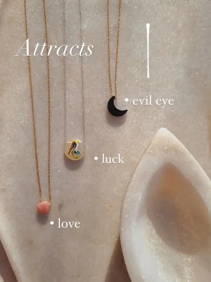 A collection of my pendants, including the hand-painted bird for luck, the Black Onyx moon for the evil eye, and a Pink Opal drop for love.