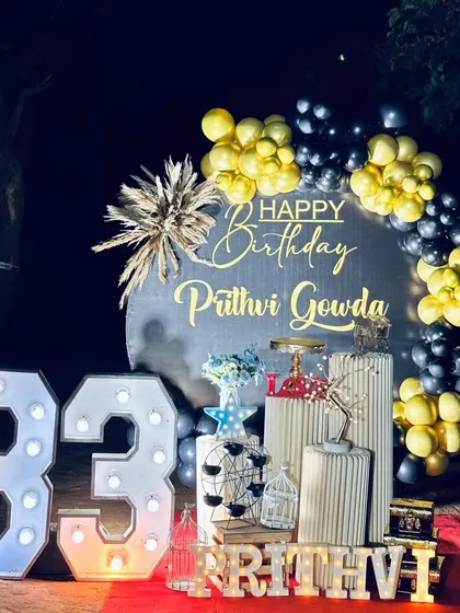 An outdoor surprise party for a 33rd birthday. This setup includes a custom backdrop, black and gold balloons, and large marquee numbers, complete with sparklers for a dramatic reveal.