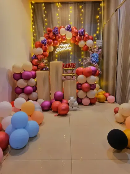 A full view of a birthday party setup with pink, purple, and cream-colored balloons. The balloons scattered on the floor add to the fun and festive environment.