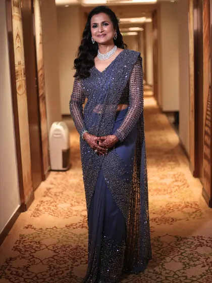 A full-length view of her elegant look. The makeup perfectly complements her sparkling navy blue saree, creating a cohesive and stunning appearance.