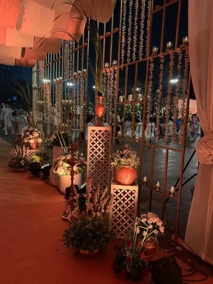 A side view of the candle-lit entrance, highlighting the intricate white pedestals and floral arrangements. The warm, flickering light creates a romantic and welcoming mood.