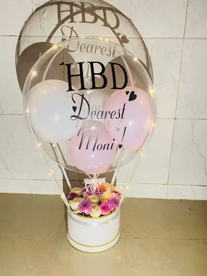 One of our best sellers, this hot air hamper features a personalized "Happy Birthday" message on a double-stuffed balloon. The base is filled with soft pink and white roses, and the entire arrangement is lit with fairy lights.