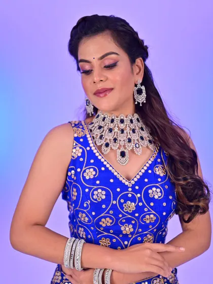 A close-up portrait showing the soft glam makeup paired with the blue lehenga. The focus is on shimmery eyes and a defined lip, creating a look that is both elegant and celebratory.
