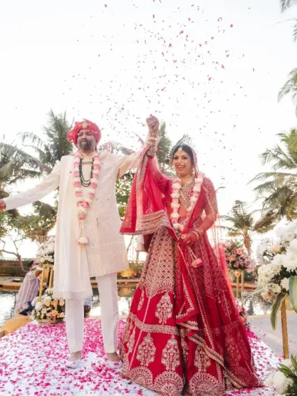 A moment of pure triumph and joy as the couple celebrates after their varmala ceremony by the pool. The shower of petals adds to the festive atmosphere of their destination wedding.