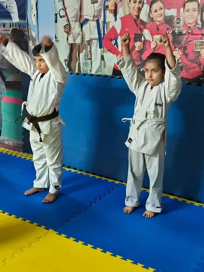 Young students in their karate gi, raising their arms during a warm-up exercise. We start every class with movements designed to prepare the body for training.
