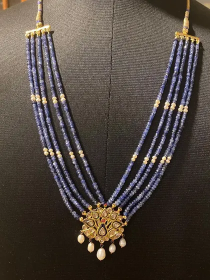 The peacock necklace displayed on a bust, giving a sense of how it wears and the beautiful V-shape formed by the sapphire strands.