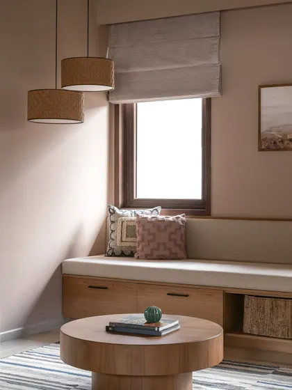 A detail of the reading nook, showing the play of light and shadow. The layered pillows and natural textures make this a comfortable and inviting corner.