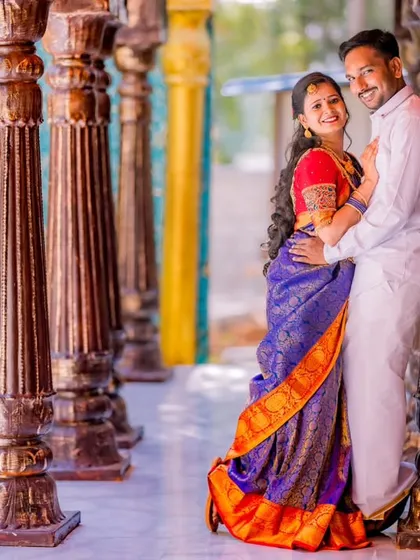 A happy, relaxed portrait of a couple in a colorful corridor. Their traditional outfits and the vibrant architecture create a joyful and energetic scene.