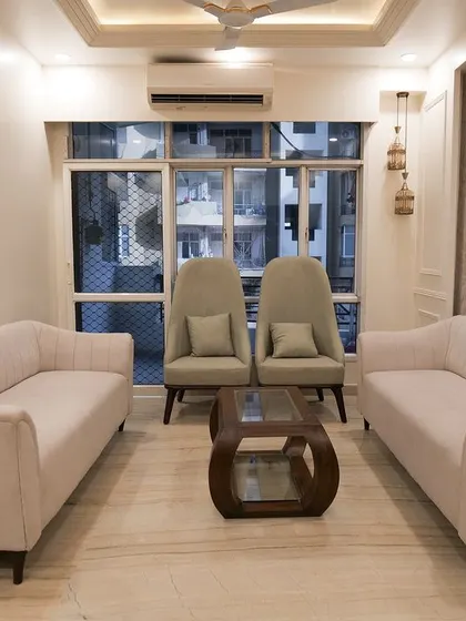 This living room from a completed project showcases a neutral color palette with comfortable sofas and high-back accent chairs, creating a balanced and inviting atmosphere.