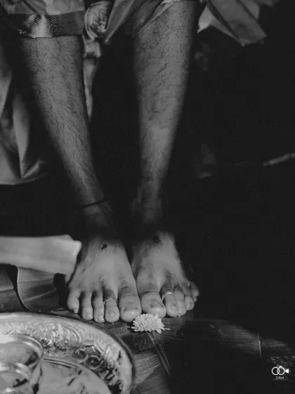 An artistic black and white detail shot of the groom's feet during a wedding ritual.
