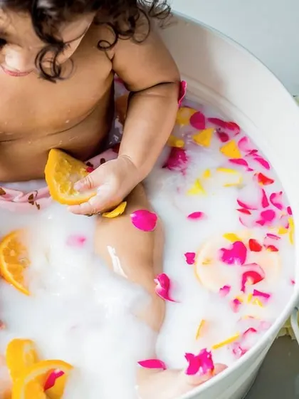 A close-up of a baby enjoying a milk bath with citrus and flower petals. I love the textures and colors in these unique and creative sessions.