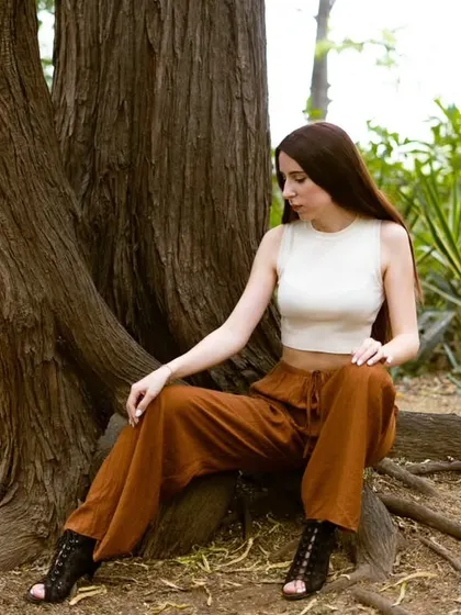 A candid-style shot from the same outdoor session, with the model seated by a tree. This demonstrates an ability to look natural and relaxed on camera in a real-world setting.