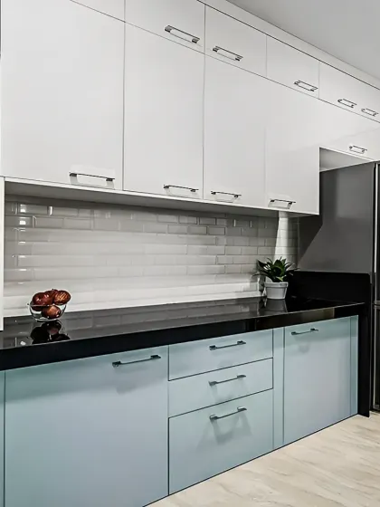 This kitchen showcases a modern two-tone design with light blue base cabinets and white overhead units. The glossy white subway tile backsplash and black hardware add a touch of contemporary style, while the layout provides plenty of storage and counter space.