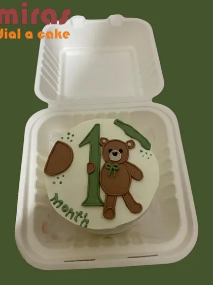 A sweet way to celebrate a baby's first month. This bento cake is decorated with a cute teddy bear and the number "1," using soft, neutral colors perfect for a milestone celebration.