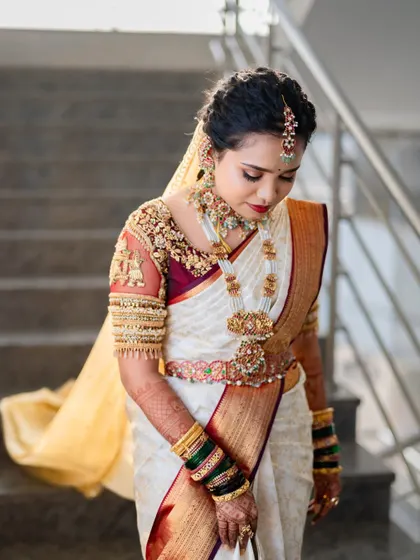 The beauty of a traditional bridal look is in its poise and grace. Here, the bride's soft glam makeup and neatly braided hair, adorned with a veil, create a truly ethereal appearance.