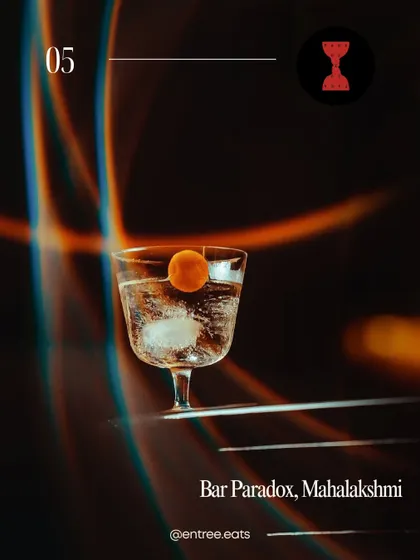An elegant, clear cocktail from Bar Paradox, Mahalaxmi. The creative lighting and minimalist presentation make this a visually striking image that stands out in the guide.