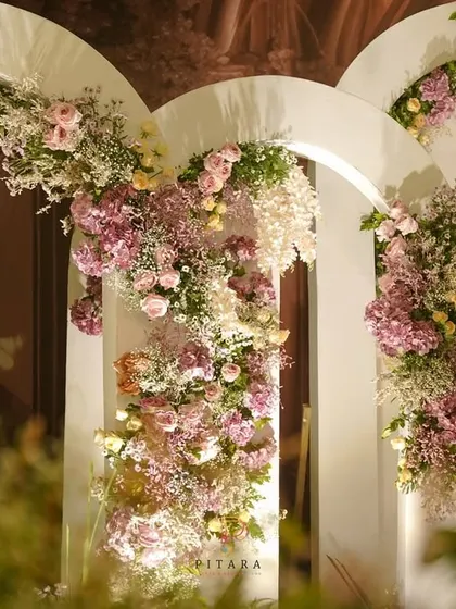 We love creating picture-perfect moments. This backdrop of layered white arches, adorned with cascading florals in soft pastel shades, served as a romantic and dreamy photo corner for guests.