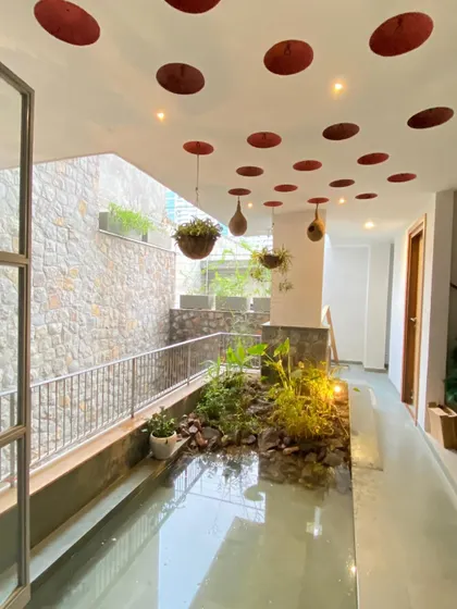 A wider view of the indoor water body, with hanging planters and earthen nests in the ceiling, designed to create a complete ecosystem within the home.