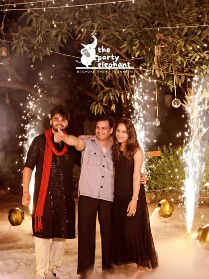 A perfect photo opportunity amidst the celebration. The guests are framed by dramatic cold pyro sparklers and a backdrop of low-lying fog, creating a truly memorable and cinematic shot.