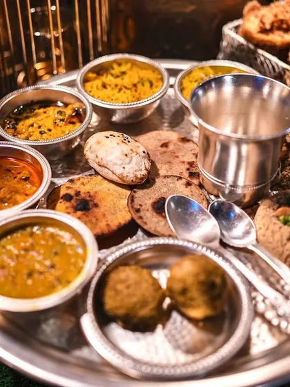 The royal Sajjan Goth Thali, a traditional Rajasthani feast. This platter features an assortment of dals, curries, breads like baati, and churma, offering a complete and authentic culinary experience.