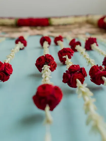 Intricate floral strings of jasmine and red roses, used as a backdrop. This traditional decoration technique adds texture, color, and a beautiful fragrance to the venue.