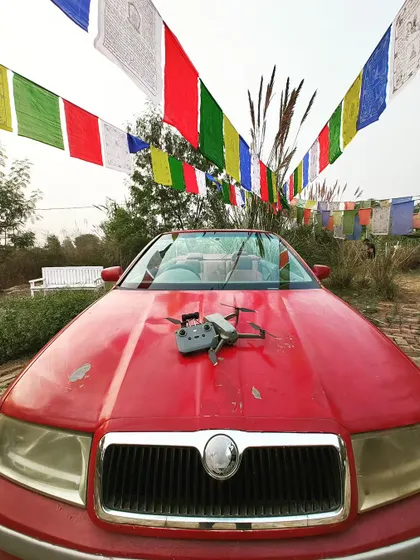 My DJI Air 2S drone ready for a pre-wedding shoot at The Picture Town. The vibrant prayer flags and classic car create a unique and colorful setting for a couple's story.