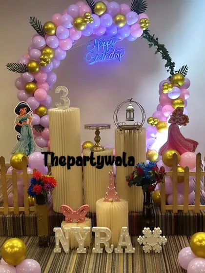 This princess setup for a 3rd birthday uses a beautiful color combination of pink and gold, with a delicate green vine on the balloon arch.