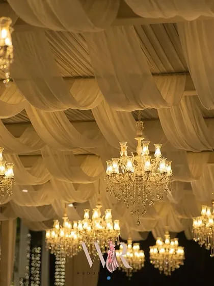 A look up at the ceiling, a sea of soft white drapes and sparkling crystal chandeliers. This kind of ceiling treatment completely transforms an outdoor space into a luxurious ballroom.